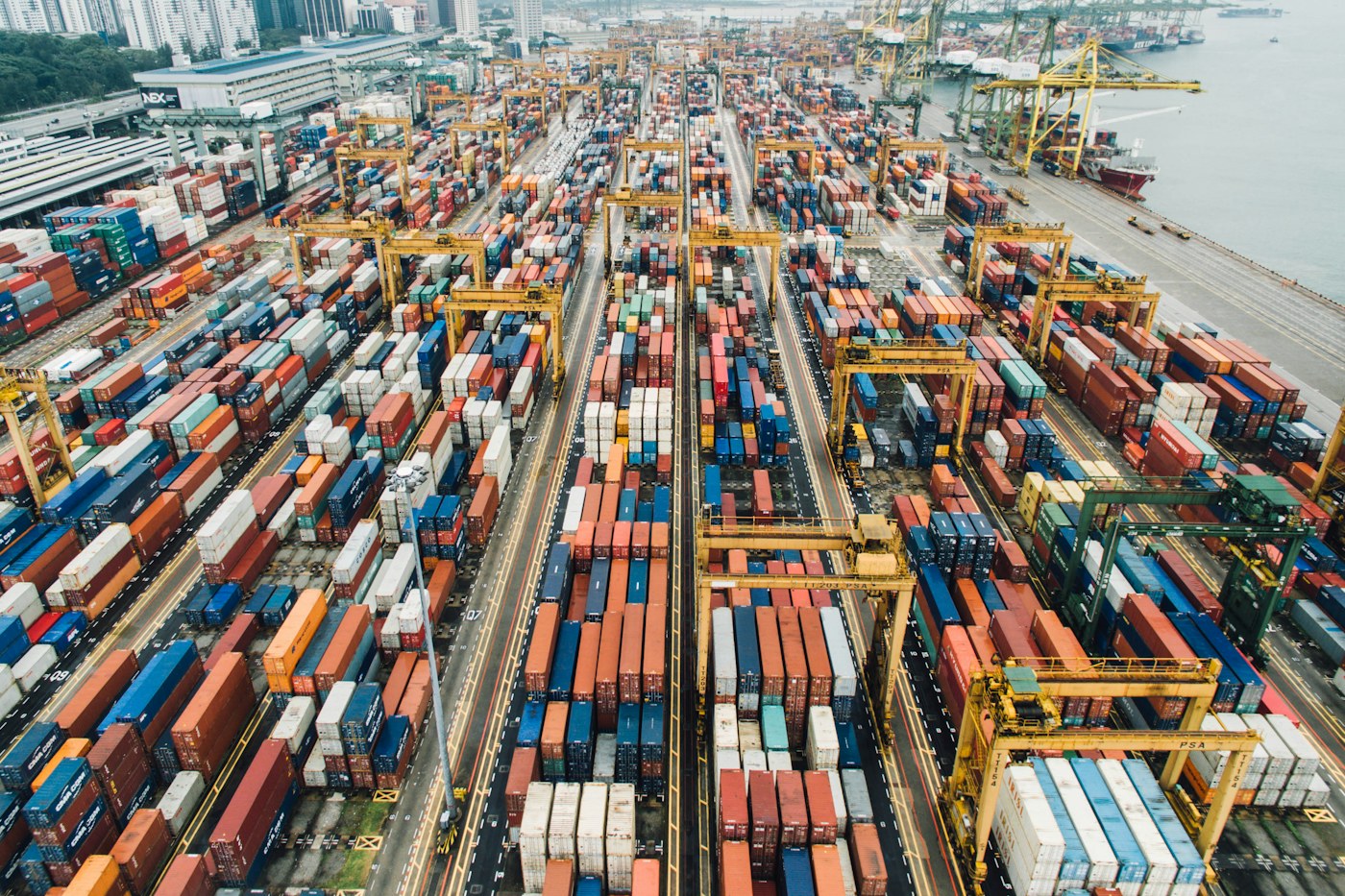 An aerial view of stacked shipping containers and cranes in Singapore.